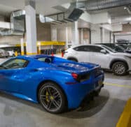 A blue sports car is parked in an indoor parking garage alongside several other vehicles.