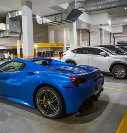 A blue sports car is parked in an indoor parking garage alongside several other vehicles.