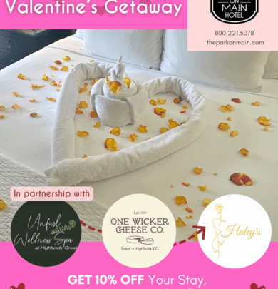 A hotel bed decorated with rose petals, towel swans, and a heart-shaped towel, promoting a Valentine's getaway with discounts at The Park on Main Hotel.